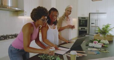 Çeşitli bayan arkadaşlar mutfak adasında organizatörü selamlıyor ve davetiye tasarımı ve kuşağı inceliyor. İşbirliği, kutlama, arkadaşlık, planlama, modern, canlı, neşeli