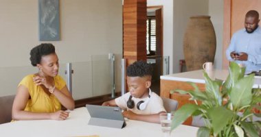 Anne ve oğlu evde tablet kullanıyor, okul projesini tartışıyorlar. Aile, ebeveynlik, eğitim, öğrenme, teknoloji, ödev