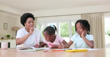 Afro-Amerikan eğitimci, akıllı telefon ve defterle evde iki kıza rehberlik ediyor. Öğrenim, eğitim, işbirliği, yaratıcılık, yetiştirme, ev, bağlılık, odaklanma