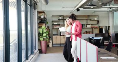 Çeşitli iş arkadaşları tabletle kutlama yapıyor ve modern açık planlı ofiste basılı belgeler hazırlıyorlar. İşbirliği, yenilik, başarı, teknoloji, başlangıç, çalışma alanı, profesyonel