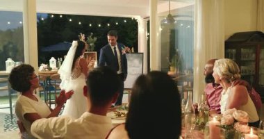 Damat gelini kapılardan ziyafet masasına geçirir, arkadaşları alkışlamak için dans eder. Düğün, kutlama, romantizm, zarafet, samimiyet, dekor, ambiyans