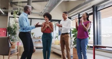 Çeşitli meslektaşlar, kart ve doğal ışık altında modern ofisteki ekip üyelerini tebrik ediyor. Kutlama, takım çalışması, başarı, işbirliği, başarı, profesyonel, ofis