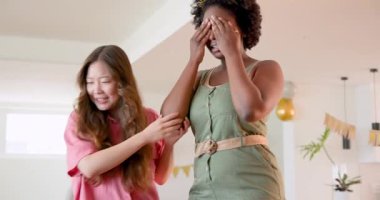 Afrikalı Amerikalı kadın ve Asyalı kadın 30. doğum gününü evde küçük pasta ve atıştırmalıklarla kutluyorlar. Kutlama, doğum günü, arkadaşlık, aydınlık, neşe, pasta, atıştırmalık