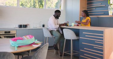 Afrika kökenli Amerikalı aile mutfakta elma dilimlerken kız sırt çantası düzenliyor. Aile, yerli, modern, yaşam tarzı, eğitim, bağlanma, gelişigüzel