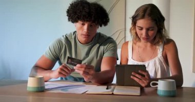 Genç çift, tablet ve belgelerle birlikte maliyeyi heyecanla inceliyor. Bütçeleme, planlama, teknoloji, takım çalışması, yaşam tarzı