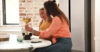 Çeşitli anne ve kızının zaferini kutlayan kupalar mutfakta topla telefon çekimleri yapıyorlar. Aile, kutlama, başarı, yakınlaşma, samimi, modern, neşeli