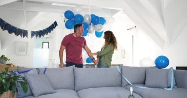 Kıdemli çift gözleri bağlı ortağa rehberlik ediyor, pankart ve balonları gösteriyorlar, evdeki ikramiyeleri denetliyorlar. Kutlama, mahrem, sürpriz, neşe, kırsal, şenlikli, yaşam tarzı