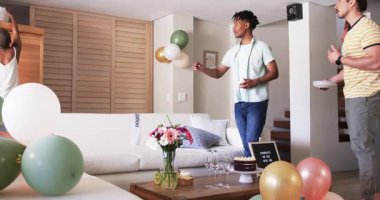 Partide, pasta ve balonlarla masayı hazırlarken, arkadaşlar kutlama için oturma odasını dekore ederken. Parti, dekorasyon, toplanma, şenlik, etkinlik, etkinlik