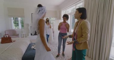 Kadın Asyalı terzi peçesini kaldırıyor, kanepeyi örtüyor, gelinliğe tül takıyor. Gelin, düğün, zarafet, kutlama, hazırlık, ahenk, sofistike