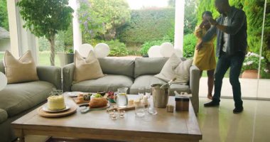 Oturma odasında kutlama pastası ve balonlarla kucaklaşan bir çift. Romantizm, mutluluk, aşk, parti, yıldönümü, birliktelik