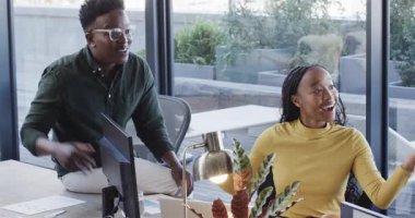 Laptop ekranına işaret eden Afro-Amerikan iş arkadaşları olumlu sonuçları kutluyor. İşbirliği, takım çalışması, yenilik, çeşitlilik, modern ofis, üretkenlik, başarı