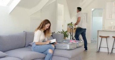 Üst düzey bir çift koltukta akıllı telefon uyarısı alıyor, defterlerini kontrol ediyor ve seyahat için bavullarını hazırlıyor. Seyahat, organizasyon, işbirliği, yaşam tarzı, modern, planlama, yerli