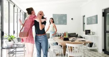 Çeşitli bayan arkadaşlar yeni geleni selamlıyor ve masaya şarap kadehlerini yerleştiriyor. Yaşam tarzı, arkadaşlık, kutlama, dekor, sosyal, neşe, sıcaklık.