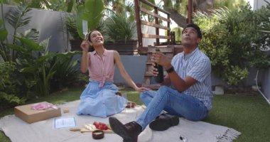 Çeşitli çiftler bahçede şampanya şişesi ve hediye kutlamasıyla kutlama yapıyorlar. Yıldönümü, kutlama, bahçe, romantizm, piknik, neşe, yeşillik, hediyeler, birliktelik