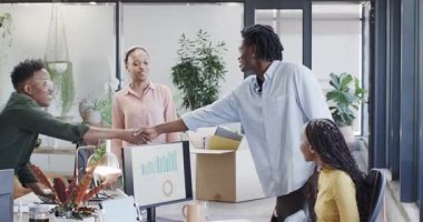 Masa kurulumu başlıyor, Afro-Amerikan iş arkadaşları açık planlama ofisindeki fabrikaları ve malzemeleri açıyor. İşbirliği, takım çalışması, işyeri, modern, profesyonel, iç mekan, çevre