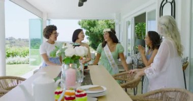 Çeşitli bayan arkadaşlar verandaya gelip ev sahiplerini kucaklıyor sonra da müstakbel gelin adayları için çay takımını hazırlıyorlar. Kutlama, dostluk, zarafet, açık hava, çiçek, sevinç, mutluluk