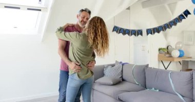 Üst sınıf çifti tavan arasında dans ediyor, balonların altında gülüyor. Romantizm, kutlama, sevgi, neşe, yakınlık, uyum, ev