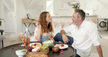 Son sınıf çifti şarap kadehleriyle kadeh kaldırıyor, açık mutfakta sohbet ederken atıştırmalık tadıyor. Romantik, kutlama, eğlence, neşe, zarafet, yaşam tarzı, iç mekan.