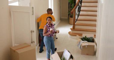 Mutlu siyah kadın ve erkek, karton kutuları ön kapıdan taşıyıp güneşli bir günde yeni bir eve taşınıyorlar. Yeni ev, mülk, mutluluk, yaşam tarzı ve ilişki kavramı.
