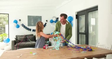 Partiden sonra baba-kız konfeti ve fincanı plastik torbaya koyup masaya sarılıyorlar. Aile, kutlama, aile içi, neşe, aile içi, neşeli, etkileşimli