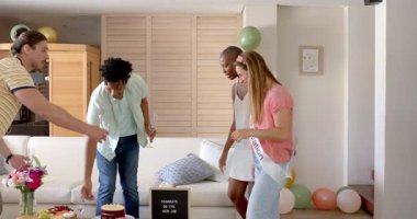 Evde kutlama, şampanya şişesini açıp kadehleri bir arada tutan arkadaşlar. Kutlama, arkadaşlık, parti, kadeh kaldırma, mutluluk, şerefe