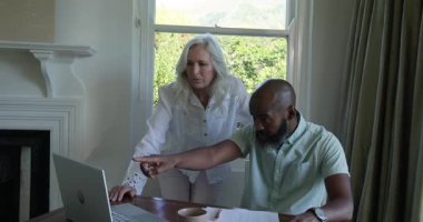 Ahşap masadaki çizelgelere işaret eden çeşitli iş arkadaşları daha sonra akıllı telefondan laptop verilerini giriyorlar. İşbirliği, akıl hocalığı, takım çalışması, kurumsal, iletişim, modern, üretkenlik