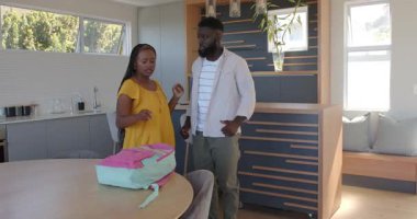 Afro-Amerikan ailesi modern evdeki okulun ilk gününü pembe sırt çantasıyla kutluyor. Aile, eğitim, kutlama, neşe, modern, yaşam tarzı, ev, takım çalışması