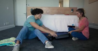 Genç çift yatak odasında bavullarını topluyor. Yolculuk için hazırlanıyorlar, evde. Seyahat, tatil, ilişki, yolculuk, valiz, hazırlık