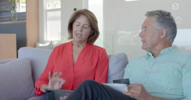 Son sınıf çifti tablete bakıyor, proje planlıyor ve oturma odasındaki kanepede kupalarla kutlama yapıyor. Arkadaşlık, rahatlama, iletişim, modern, rahat, evcil, yaşam tarzı