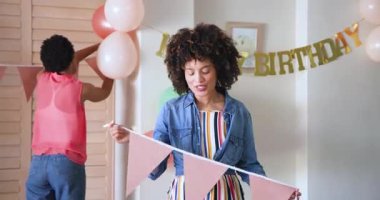 Doğum günü partisi için dekorasyon, evde balonlu pankartlar asan çeşitli kadın çiftler. Kutlama, festival, parti planlaması, dekorasyon, arkadaşlar, etkinlik