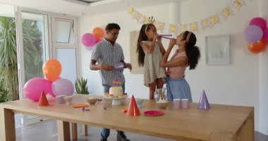 Çeşitli arkadaşlar doğum gününü parti şapkaları ve neşeli gülümsemelerle beyaz pasta etrafında kutluyorlar. Kutlama, sevinç, toplanma, pasta, aile, canlı, mimari, şenlik