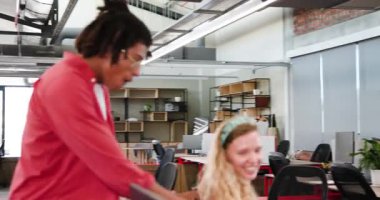 Çeşitli iş arkadaşları tekerlekli sandalyeyi itiyor ve parlak açık planlı ofiste monitörlerle gülüyorlar. Çalışma alanı, modern, işbirlikçi, iş arkadaşları, oyuncu, takım çalışması, bölümler