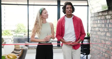 Çeşitli iş arkadaşları ofis salonunda balonlar ve televizyonla kırmızı kurdele kesiyorlar. Kutlama, tören, açılış, işbirliği, takım çalışması, kurumsal, çağdaş