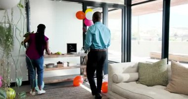 Çeşitli iş arkadaşları modern ofis alanında takım üyelerini renkli balonlar ve abur cuburlarla kutluyor. Kutlama, takım çalışması, başarı, ofis, işbirliği, yoldaşlık, neşe