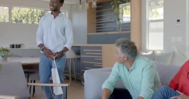 Son sınıf çifti, kız üstüne kanepede oturmuş hediye paketini sunuyorlar, paketleri açıyorlar. Aile, kutlama, sıcaklık, birliktelik, neşe, iç mekan, yaşam tarzı.