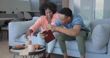 Afrika kökenli Amerikalı bir çift modern mutfakta birlikte yürüyor, ellerinde kitap tutuyorlar, evde. ilişki, ev hayatı, yaşam tarzı, gündelik, ev, iç mekan