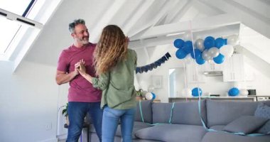 Balonla çizilmiş çatı katına giren çift gri kanepede dans ederken el ele tutuşuyorlar. Romantizm, kutlama, yakınlık, dekor, modern, boş zaman, sevgi