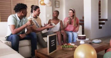 Arkadaşlar evde kutlama yapıyorlar. İçkiler ve pastayla. Kutlama toplantılarının tadını çıkarıyorlar. Kutlama, arkadaşlık, parti, tatlı, içecek, eğlence