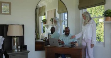 Dizüstü bilgisayardaki seyahat programını inceledikten sonra yaşlı çift seyahat için bavullarını hazırlıyor. İşbirliği, planlama, seyahat, toplanma, boş zaman, ev ofisi, yaşam tarzı