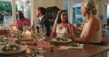 Çeşitli konuklar şampanya kadehleri kaldırıyor salata dağıtırken yemek masasında evliliğe kadeh kaldırıyorlar. Kutlama, toplanma, şenlik, zarafet, çeşitlilik, neşe, yoldaşlık