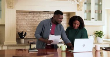 Yetişkin çiftler mutfakta dizüstü bilgisayar ve kahve fincanlarıyla belgeleri gözden geçiriyorlar. Aile, yaşam tarzı, planlama, takım çalışması, işbirliği, ev