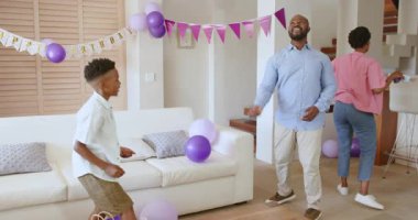 Anne abur cubur hazırlarken baba oğul balonlarla oynuyorlar. Aile, bağ, eğlence, kutlama, ebeveynlik, mutluluk.