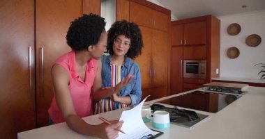 Çeşitli kadın çiftler mutfak tezgahında evrakları inceliyor, sabah kahvenin tadını çıkarıyorlar, evde. ev, yaşam tarzı, kağıt işleri, gündelik