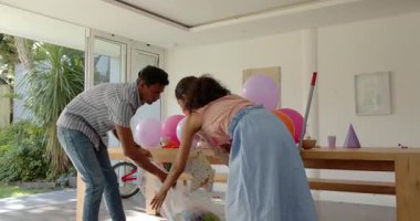 Çeşitli çiftler doğum günü pastası ve ev partisinde renkli balonlar düzenliyor. Kutlama, balonlar, toplanma, şenlik, parti, dekor, ışık, neşe