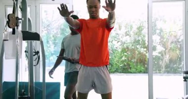 Kürek çekme makinesinde egzersiz yapan Afro-Amerikan erkekleri spor salonunda kararlı ve odaklanmış durumdalar. Fitness, egzersiz, eğitim, kararlılık, egzersiz, motivasyon