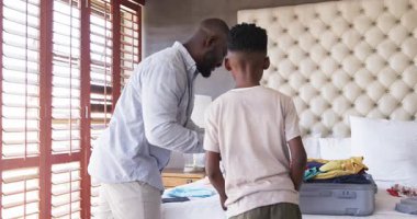 Yatakta bavul hazırlamak, tatilde giyecek organize etmek, evde birlikte gülümsemek. Seyahat, hazırlık, macera, tatil, aile zamanı, bagaj