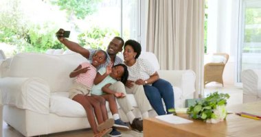 Modern yaşam evinde dans eden Afro-Amerikan ailesi, parlak pencereler ve yeşil bitkilerin tadını çıkarıyorlar. Neşeli, dans, aile, modern, canlı, rahat, yeşil