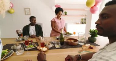 Çeşitli arkadaşlar evde öğle yemeğinin tadını çıkarıyor, kahkahalar ve sohbetler ediyorlar. Arkadaşlık, toplanma, birliktelik, yemek, kaynaşma, toplum