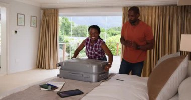 Afro-Amerikalı çift birlikte tatile hazırlanmak için bavullarını hazırlıyorlar. Seyahat, valiz, macera, yolculuk, tatil