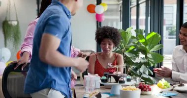 Kurdele kesme törenine katılan çeşitli iş arkadaşları masa gösterimi ve şenlik dekoruyla kapalı mekanda sergileniyor. Kutlama, takım çalışması, olay, dekor, pasta, kahkaha, modern